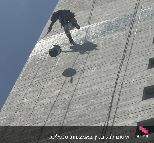 אדם מנקה קיר חיצוני של בניין גבוה